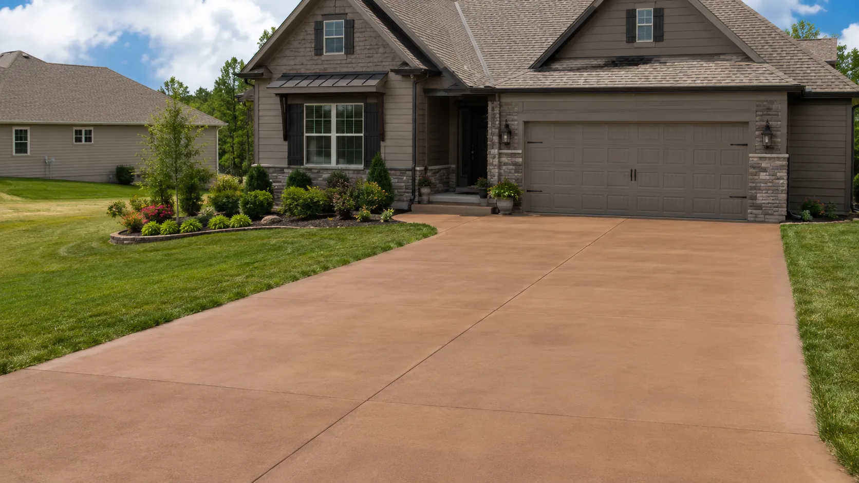 Warm-toned colored concrete driveway in front of a home